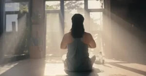 woman meditating in front of window with sunlight