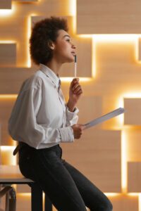 business woman thinking with pen in hand and notebook in theother.